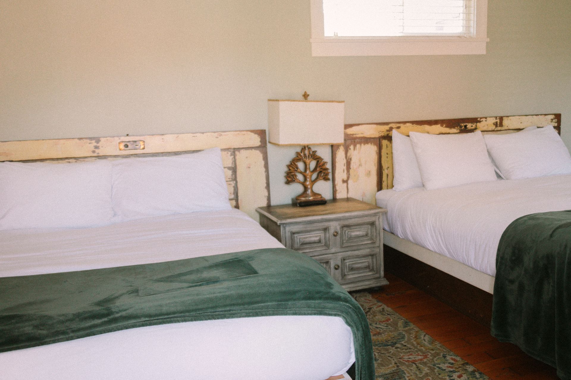 A bedroom with two beds , a nightstand and a lamp.