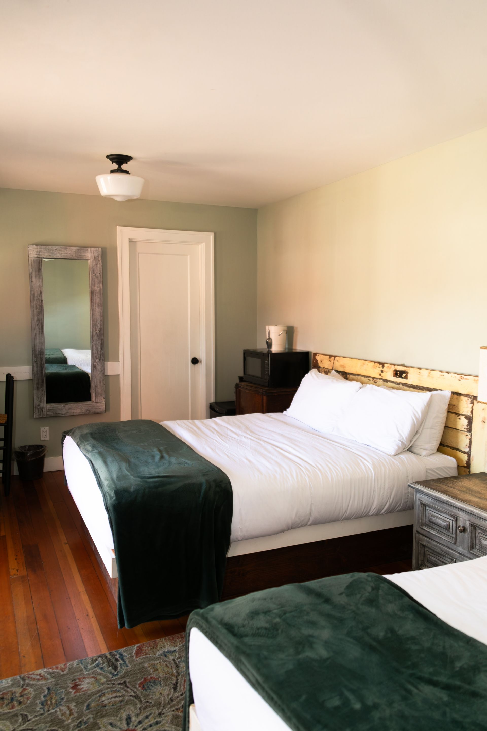 A bedroom with two beds , a nightstand and a lamp.