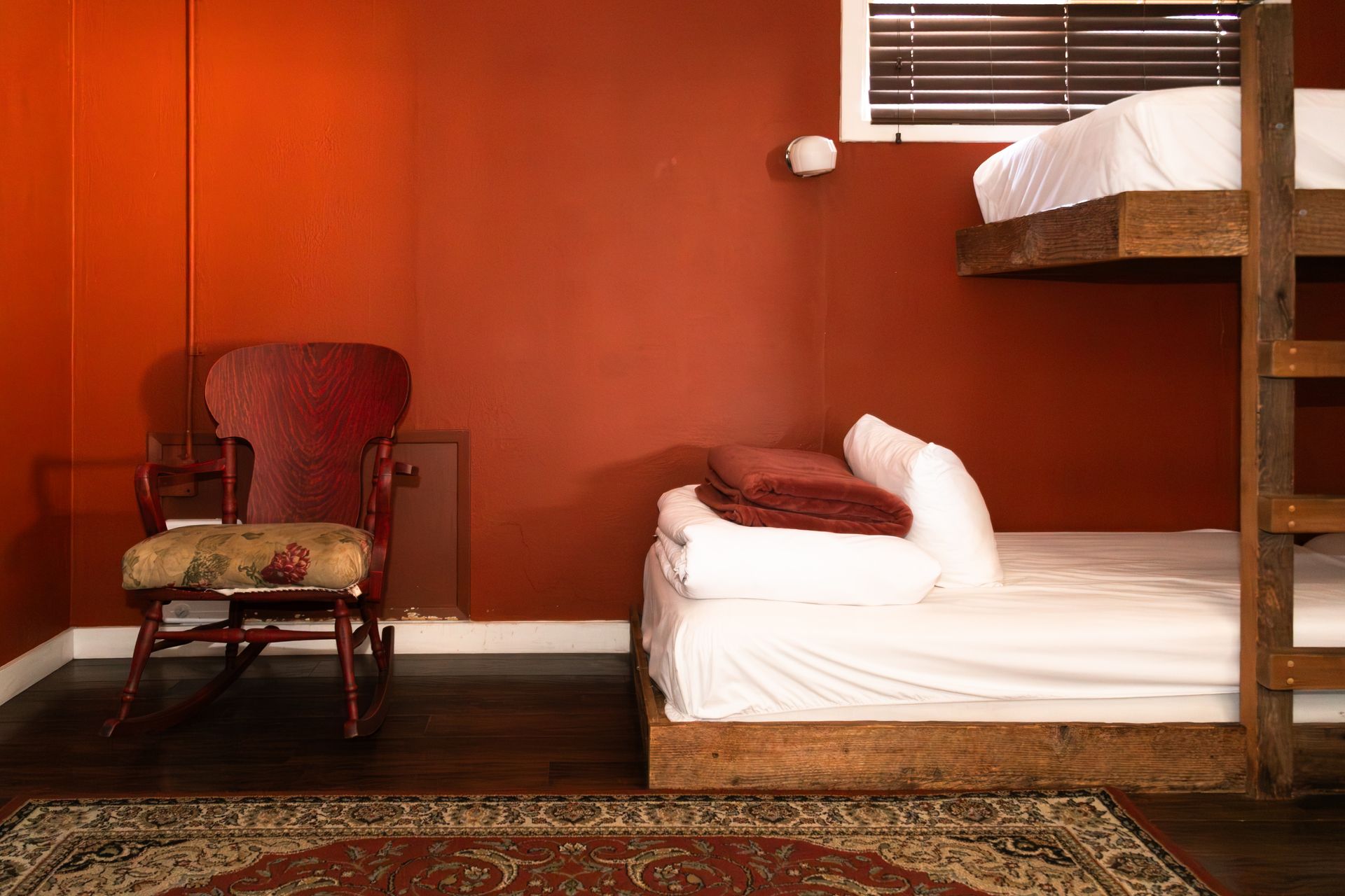 A room with four bunk beds and a rocking chair.