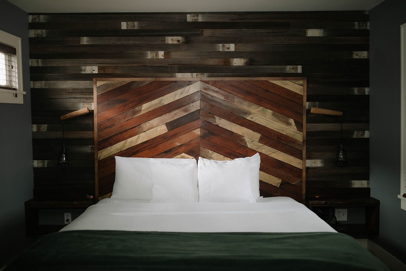A bed with white sheets and a wooden headboard in a hotel room.