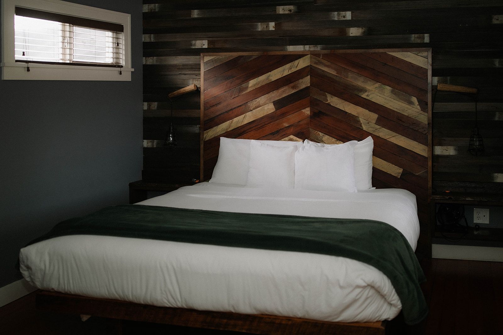 A bed with white sheets and a wooden headboard in a hotel room.