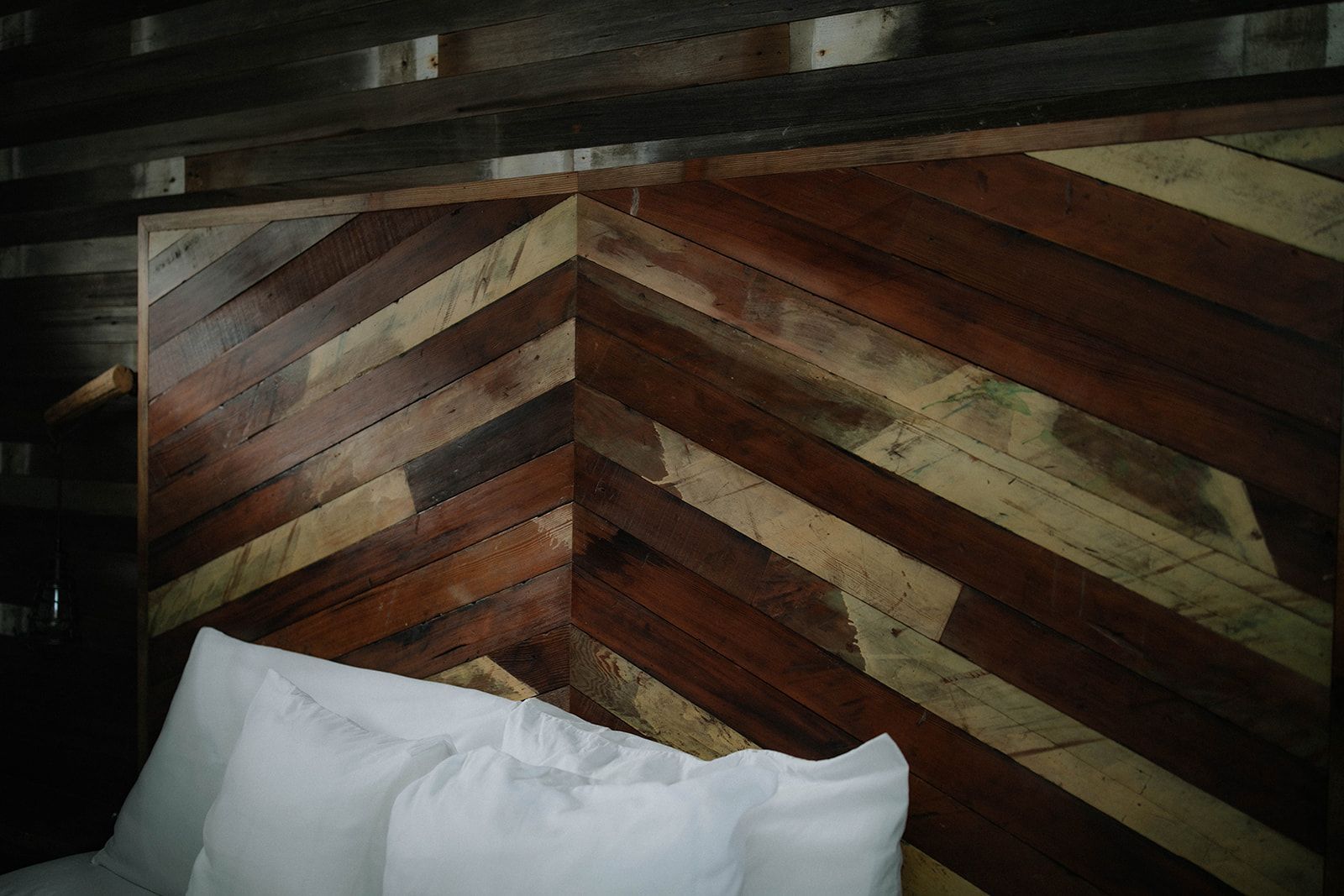 A bed with white sheets and a wooden headboard.