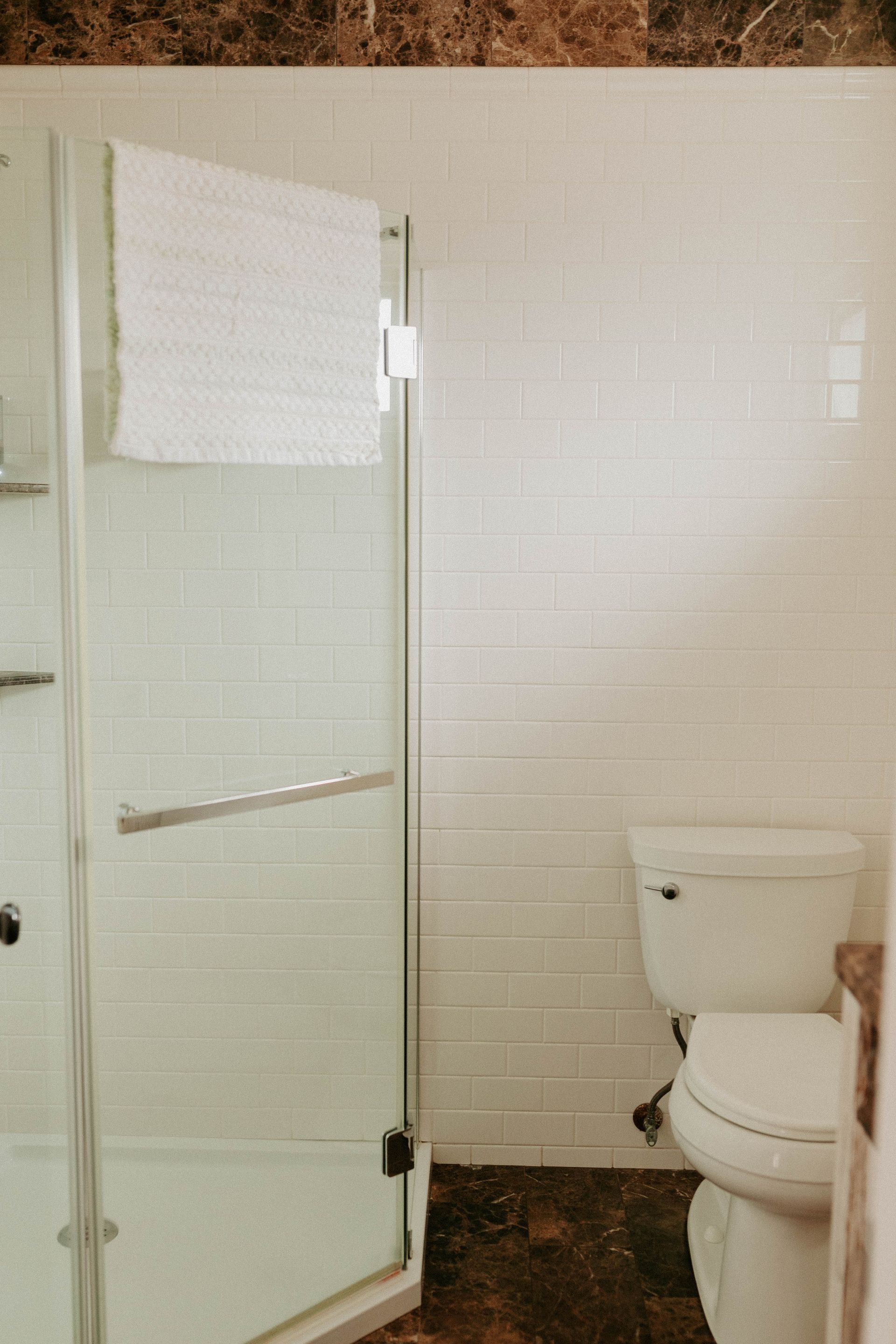 A bathroom with a toilet , shower , and towel rack.