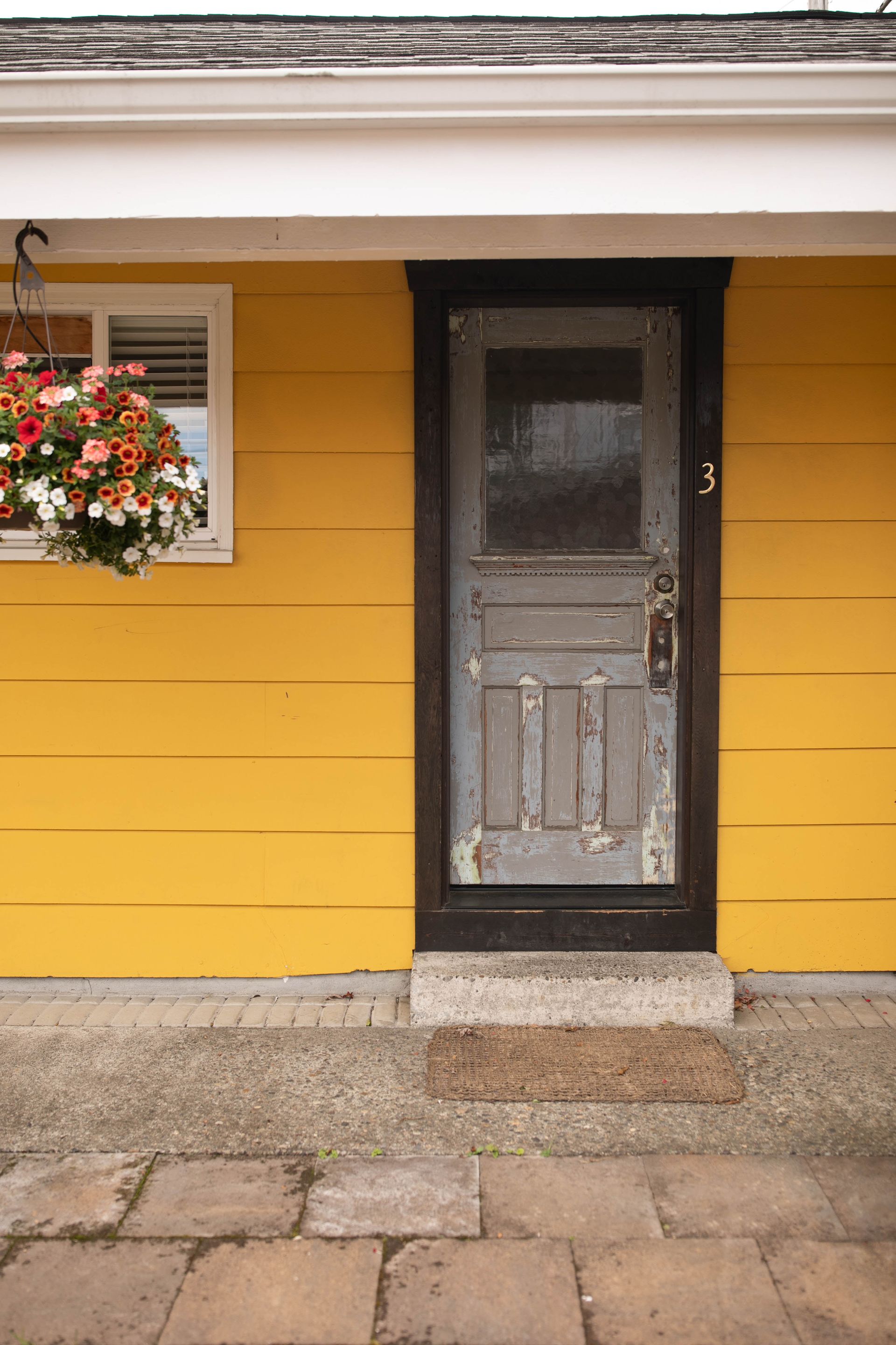 A yellow house with a door that has the number 3 on it