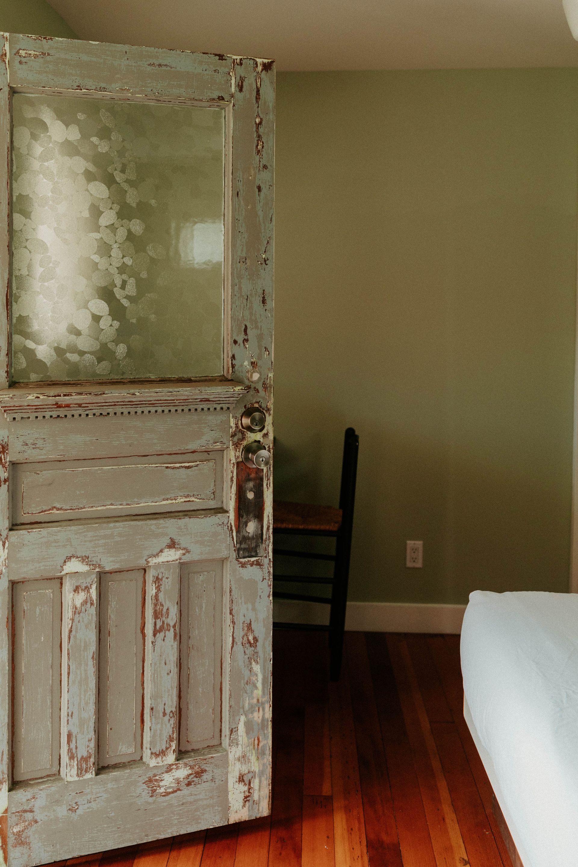 A bedroom with a bed and a chair and a door that is open.