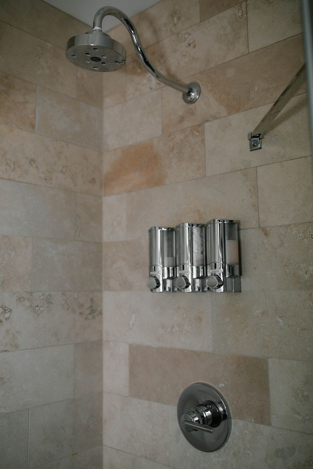 A shower with a shower head and soap dispensers on the wall