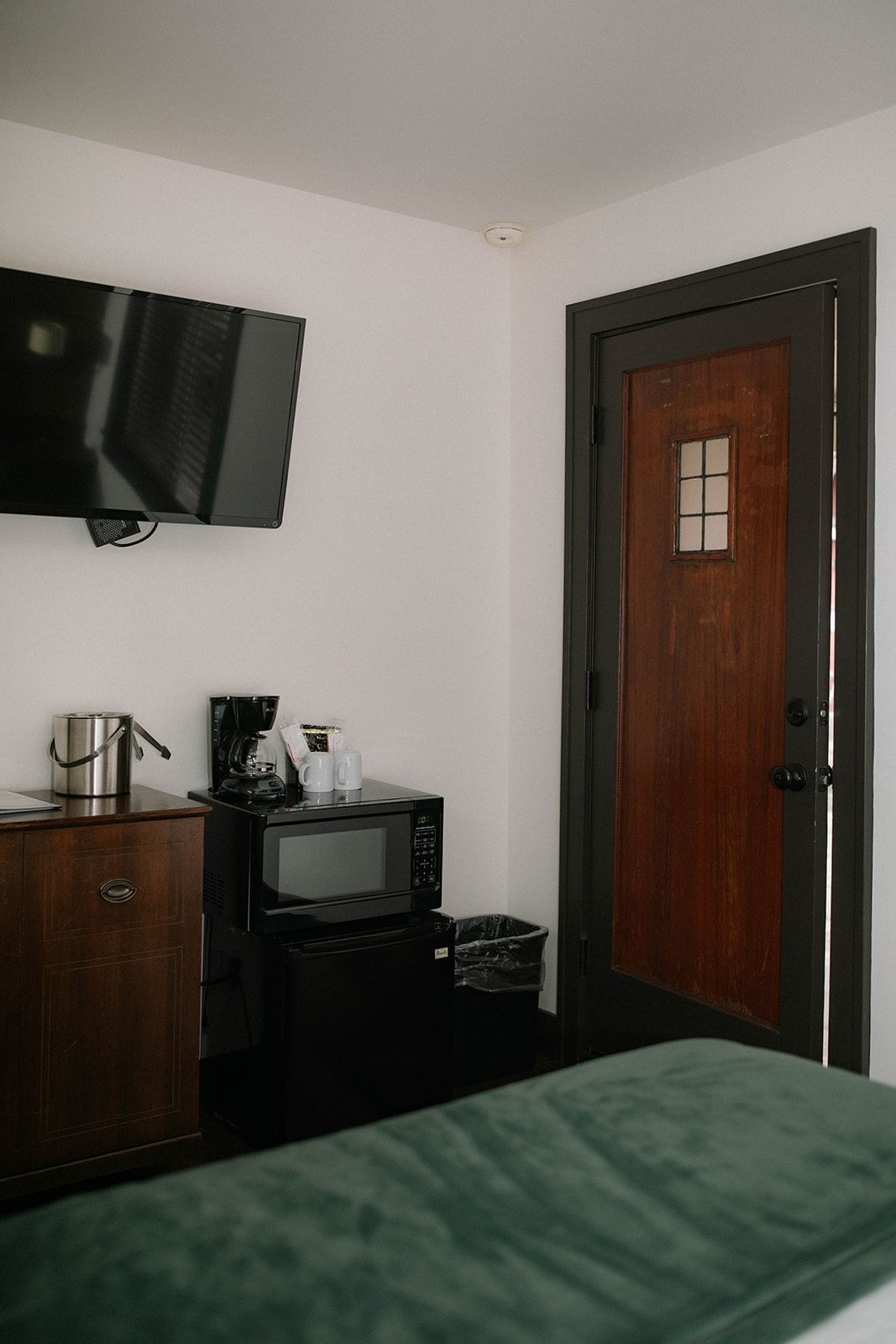 A hotel room with a bed , television , microwave and door.