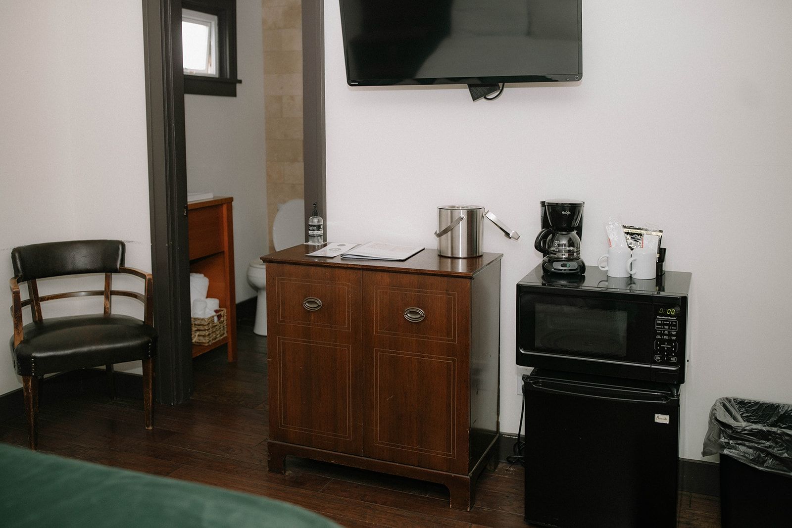 A hotel room with a dresser , chair , microwave , and television.