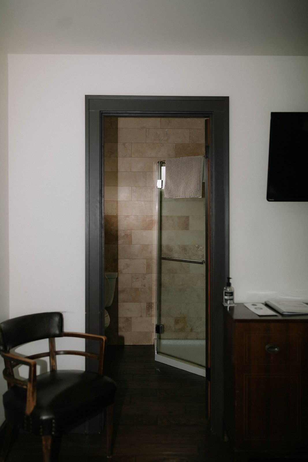 A chair is sitting in a room next to a door leading to a bathroom.