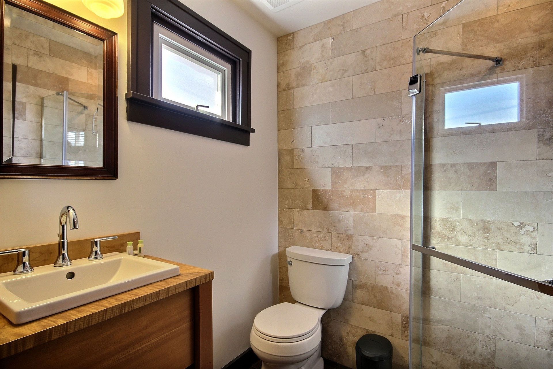 A bathroom with a toilet , sink and shower.