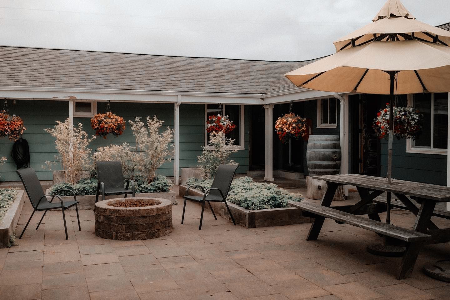 A patio with a fire pit and umbrellas in front of a house