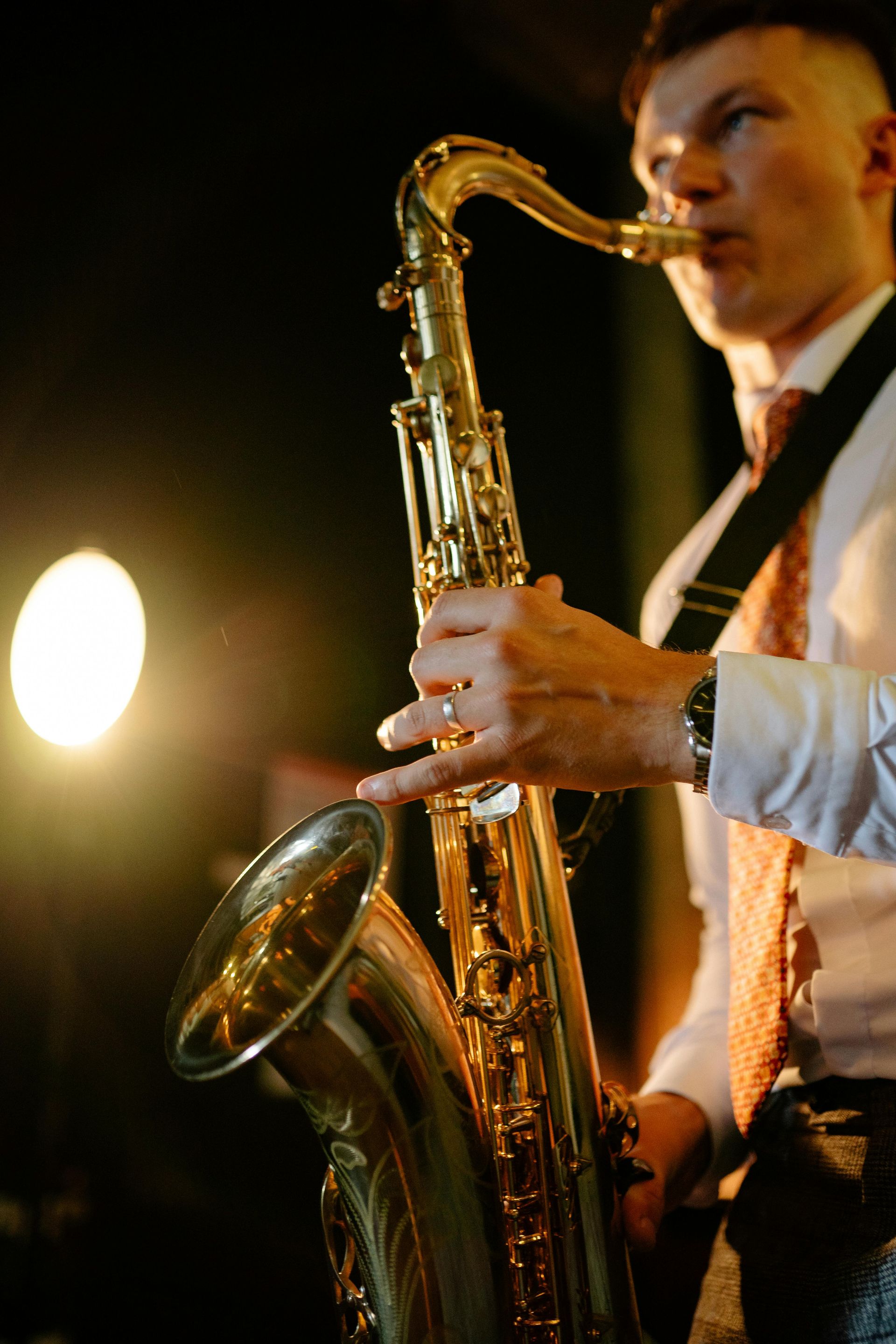 A man in a suit and tie is playing a saxophone.