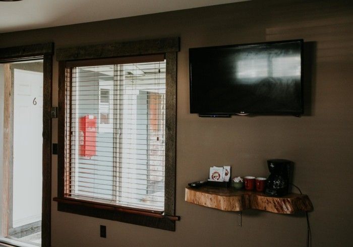 A living room with a window and a flat screen tv on the wall.