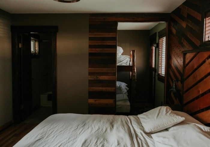 A bedroom with a bunk bed and a bed with white sheets.