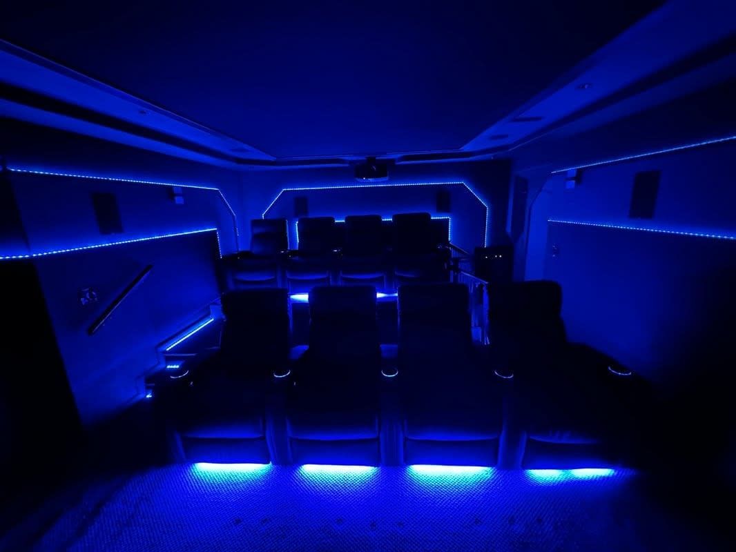Blue LED-lit party bus interior with empty seats and glowing floor lights