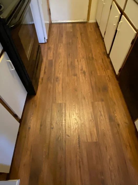 Narrow kitchen hallway with wooden floor and cream cabinets on both sides