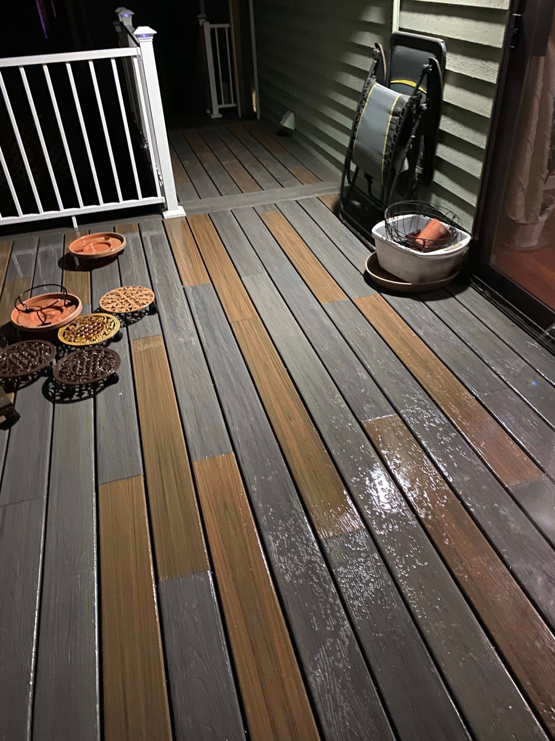Snow-dusted wooden porch with potted plants, a white railing, and a small electric grill on the right.