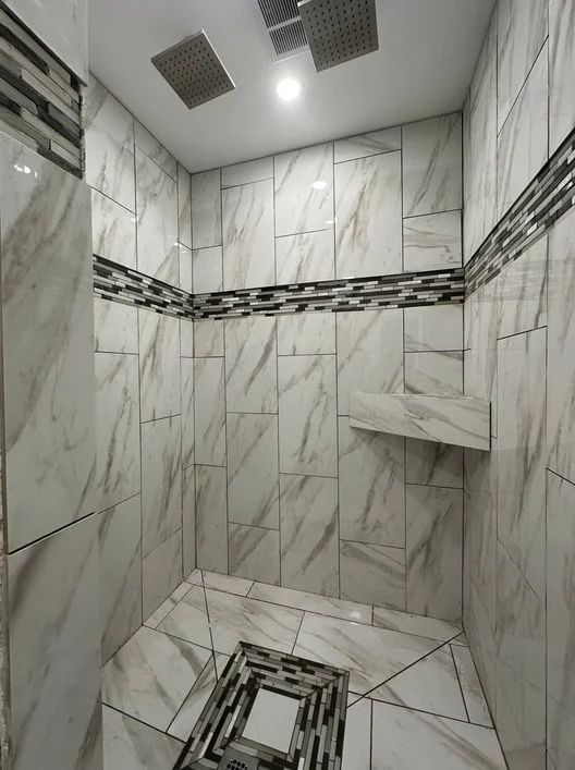 Small tiled bathroom shower with marble-look walls, floor drain, and recessed ceiling lights