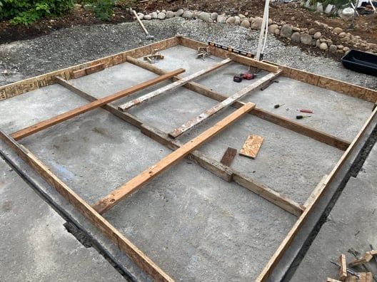 Concrete foundation slab with wooden framing formwork at a construction site.