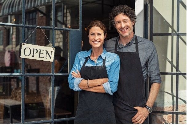 A Man and A Woman Are Standing in Front of An Open Sign — Linda Emery & Associates In Gosford, NSW