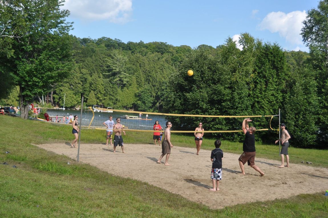 A group of people are playing volleyball on a sandy court