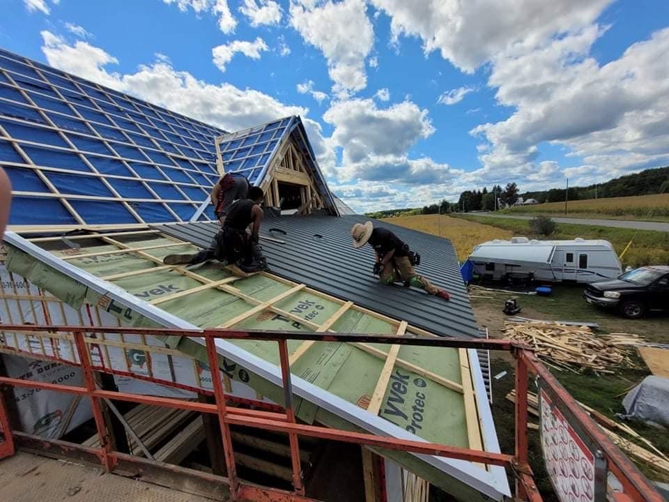 Roofers installing shingles on a house roof under a blue sky.