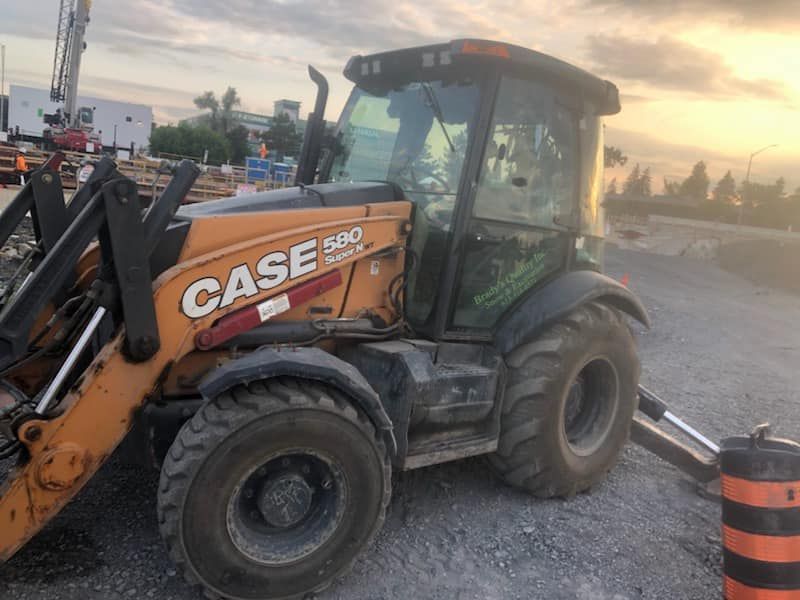Case 580 backhoe in construction site setting, orange and black, muddy.