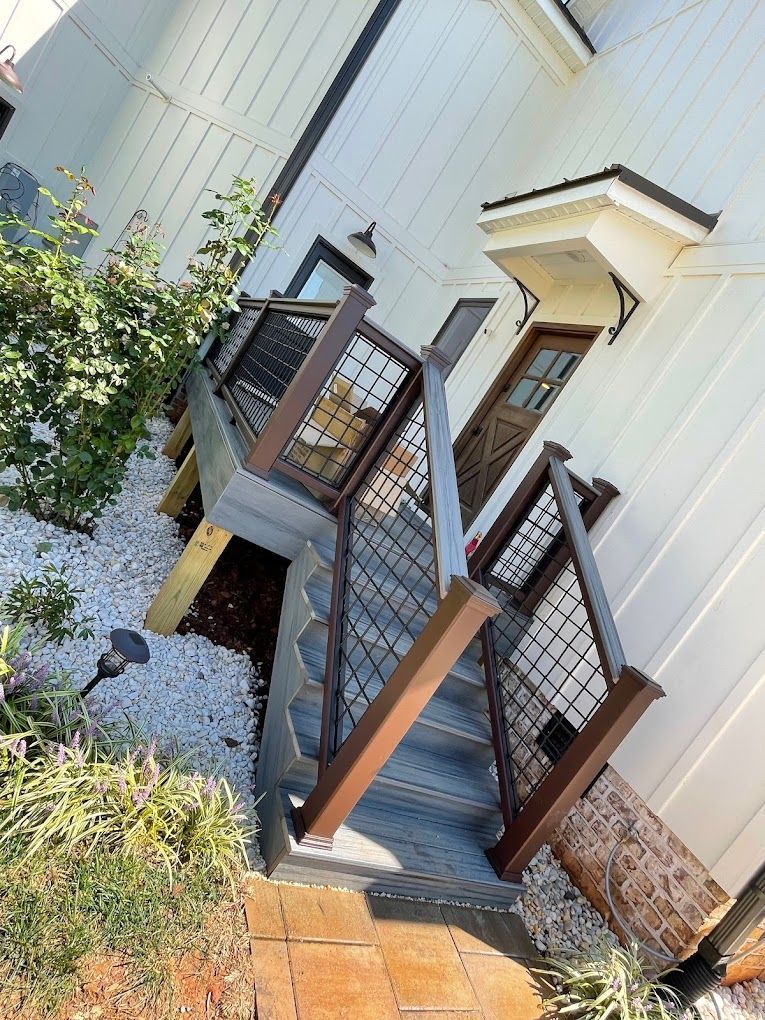 A white house with a wooden deck and stairs leading up to it.