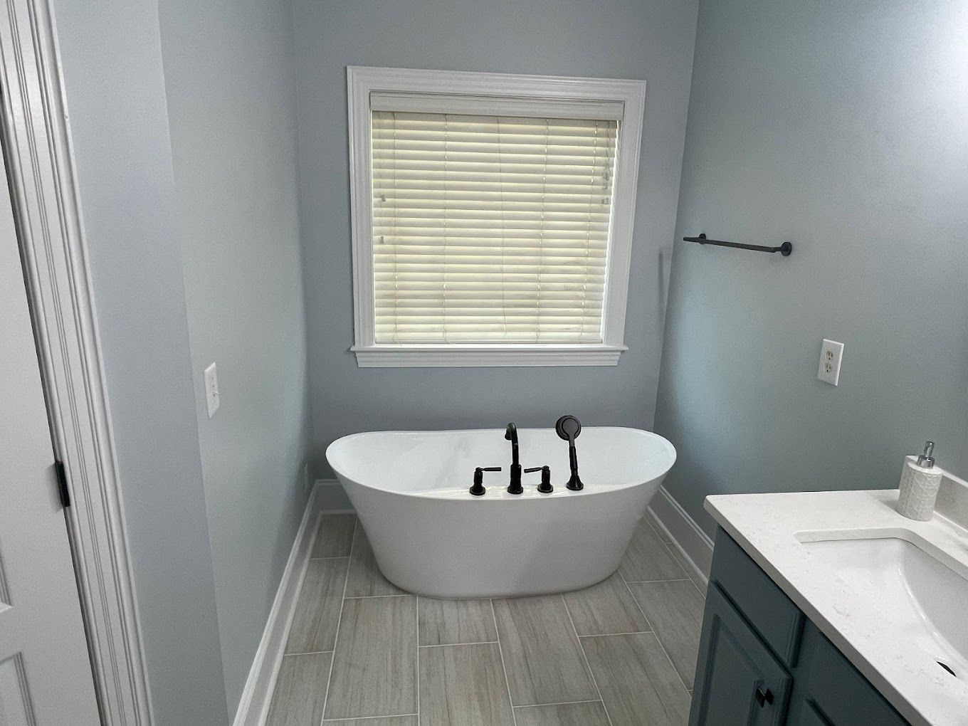 A bathroom with a bathtub , sink , and window.