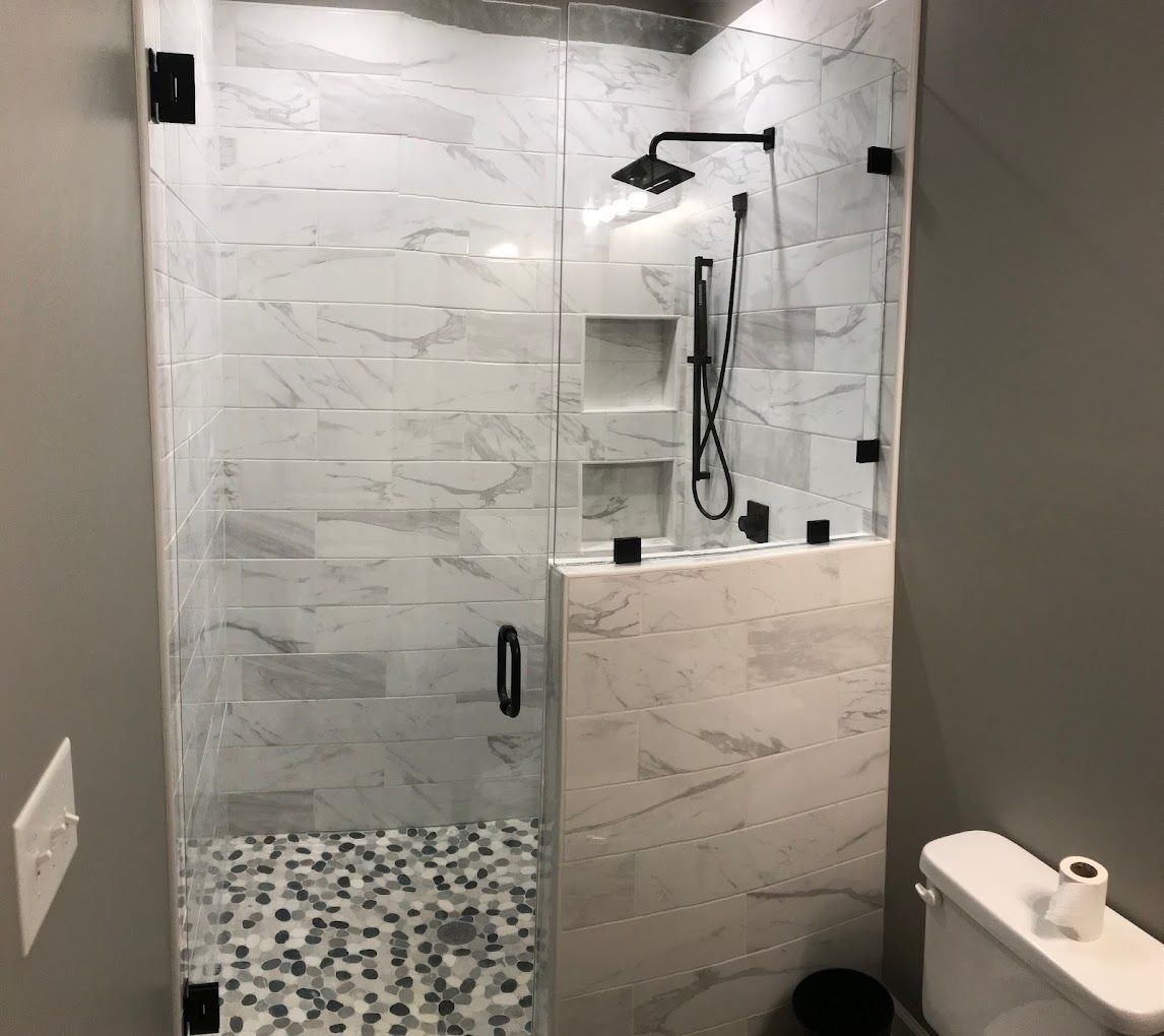 A bathroom with a toilet and a shower with a glass door.