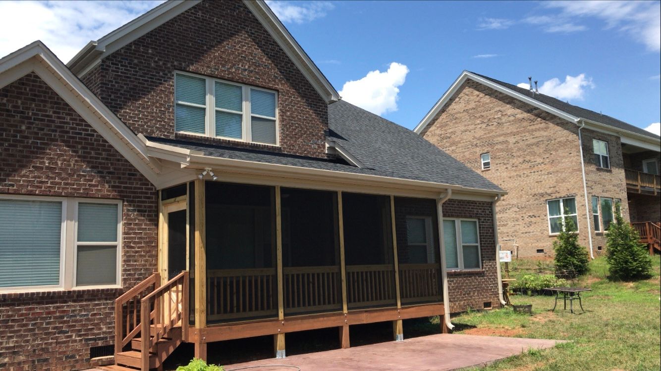 A brick house with a screened in porch and stairs
