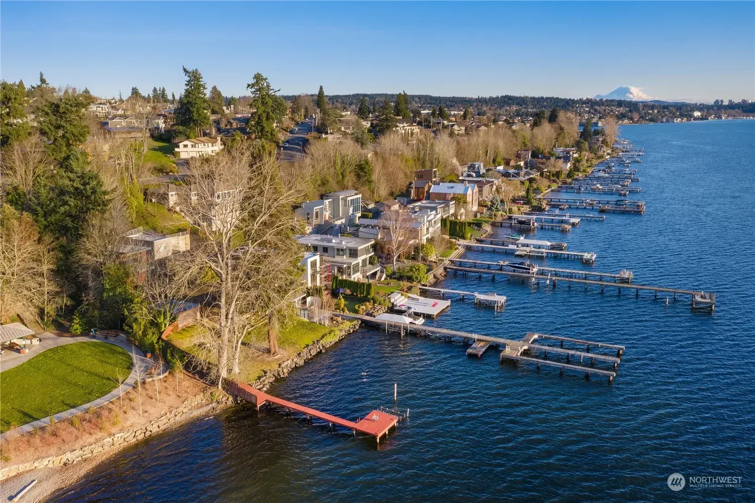 An aerial view of a lake with a dock and houses on the shore.