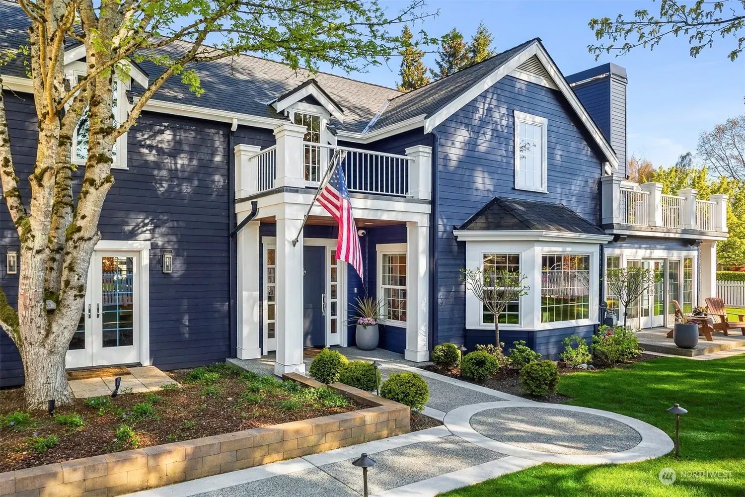 A large blue house with an american flag on the front porch.