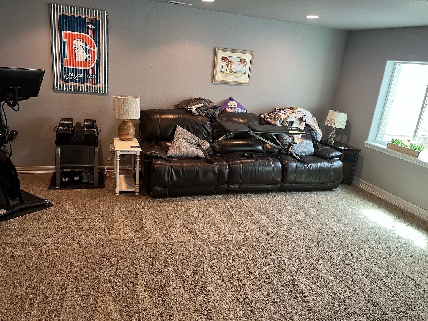 A living room with a couch and a poster on the wall.
