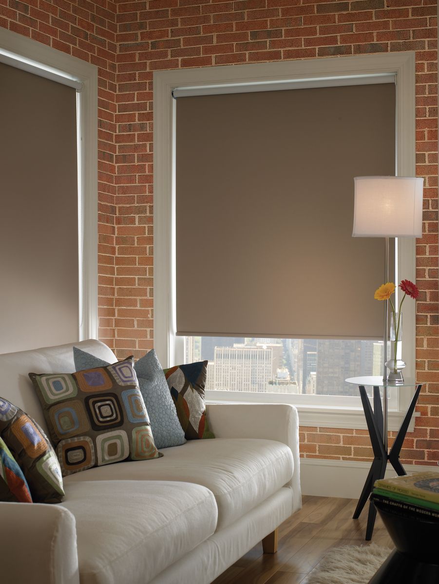 Living room with brown blinds, exposed brick wall, white sofa, and a lamp.