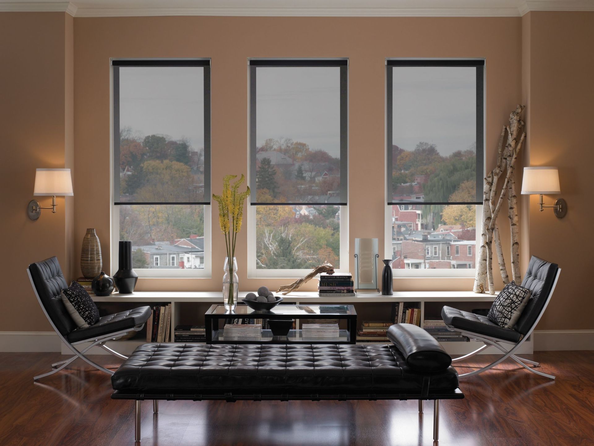 Living room with three windows, black shades, modern furniture, and cityscape view.
