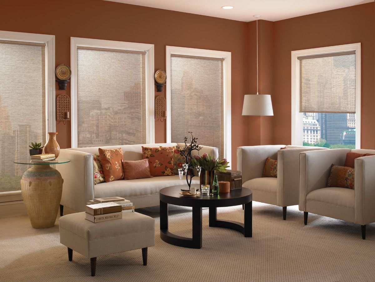 Living room with orange walls, cream furniture, and window coverings.