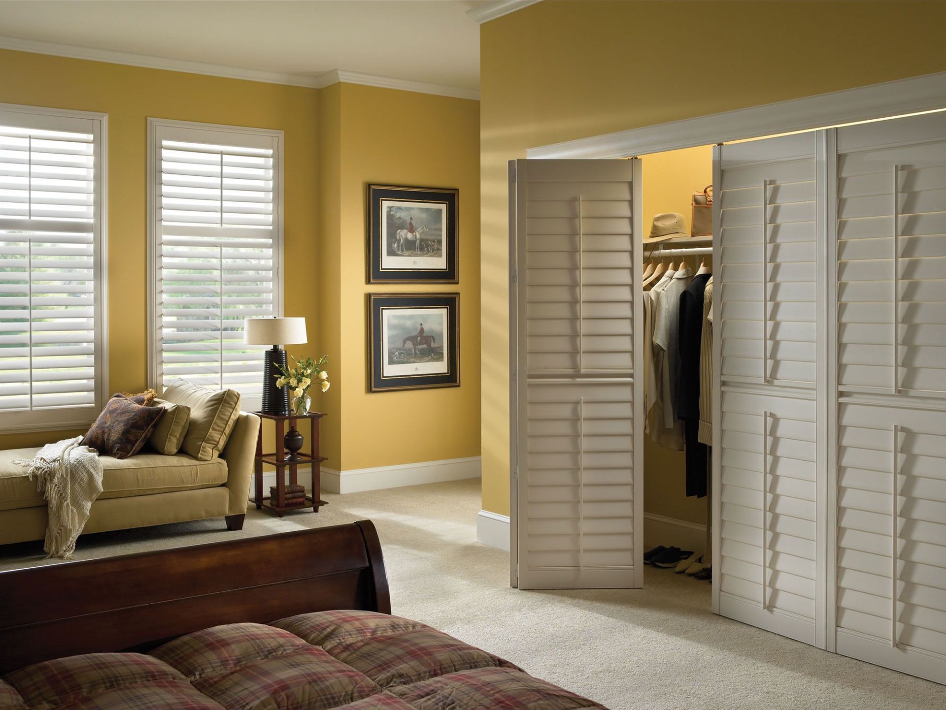 Bedroom interior with yellow walls, white shutters, and a closet.