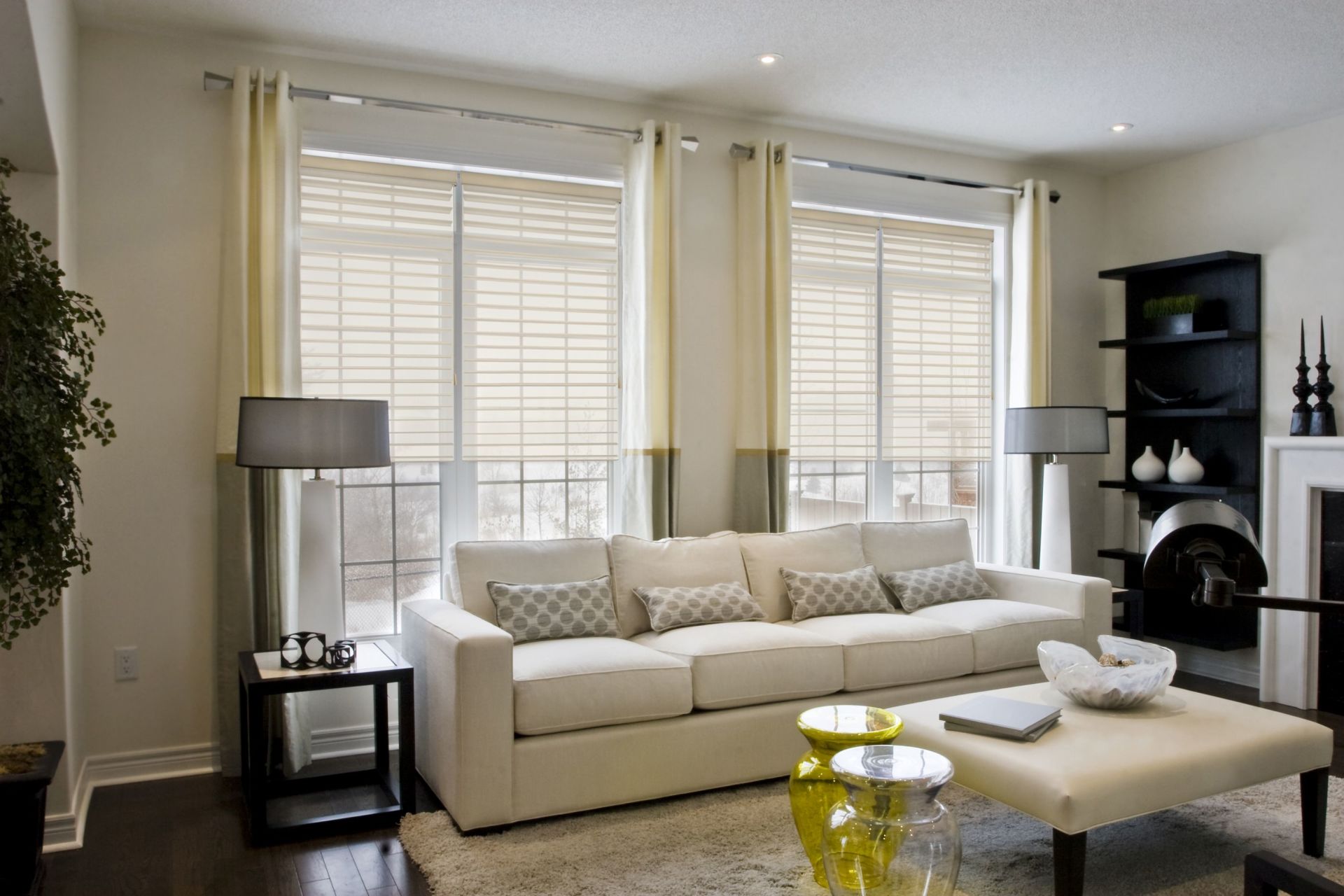 Living room with a white sofa, neutral-colored curtains, and dark wood floors.
