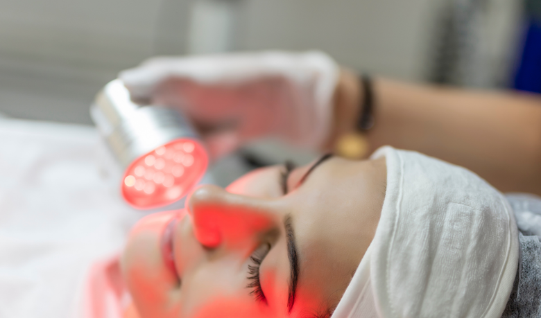 A woman is getting a red light treatment on her face.