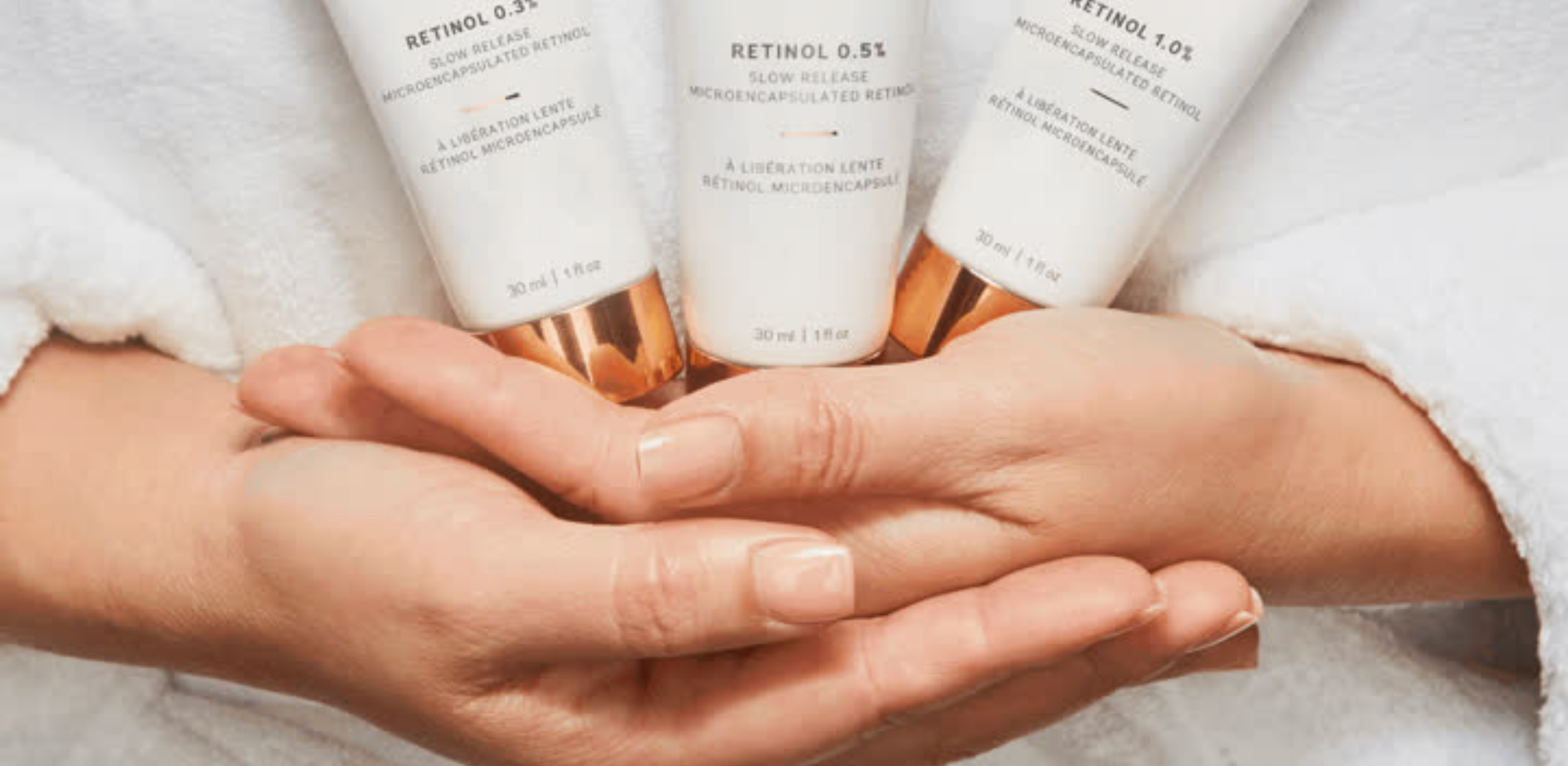 A woman is holding three bottles of lotion in her hands.