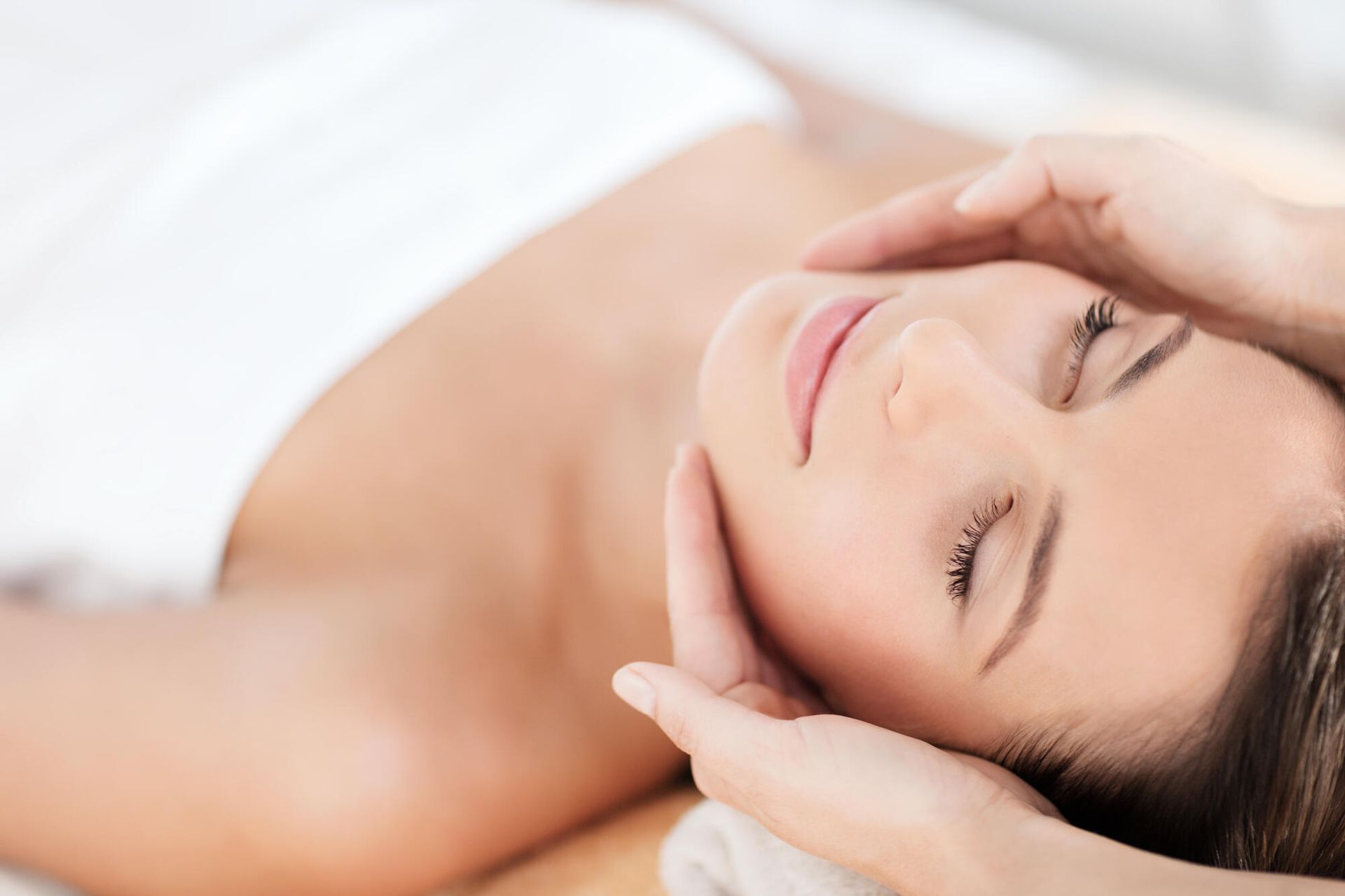 A woman is getting a facial massage at a spa.