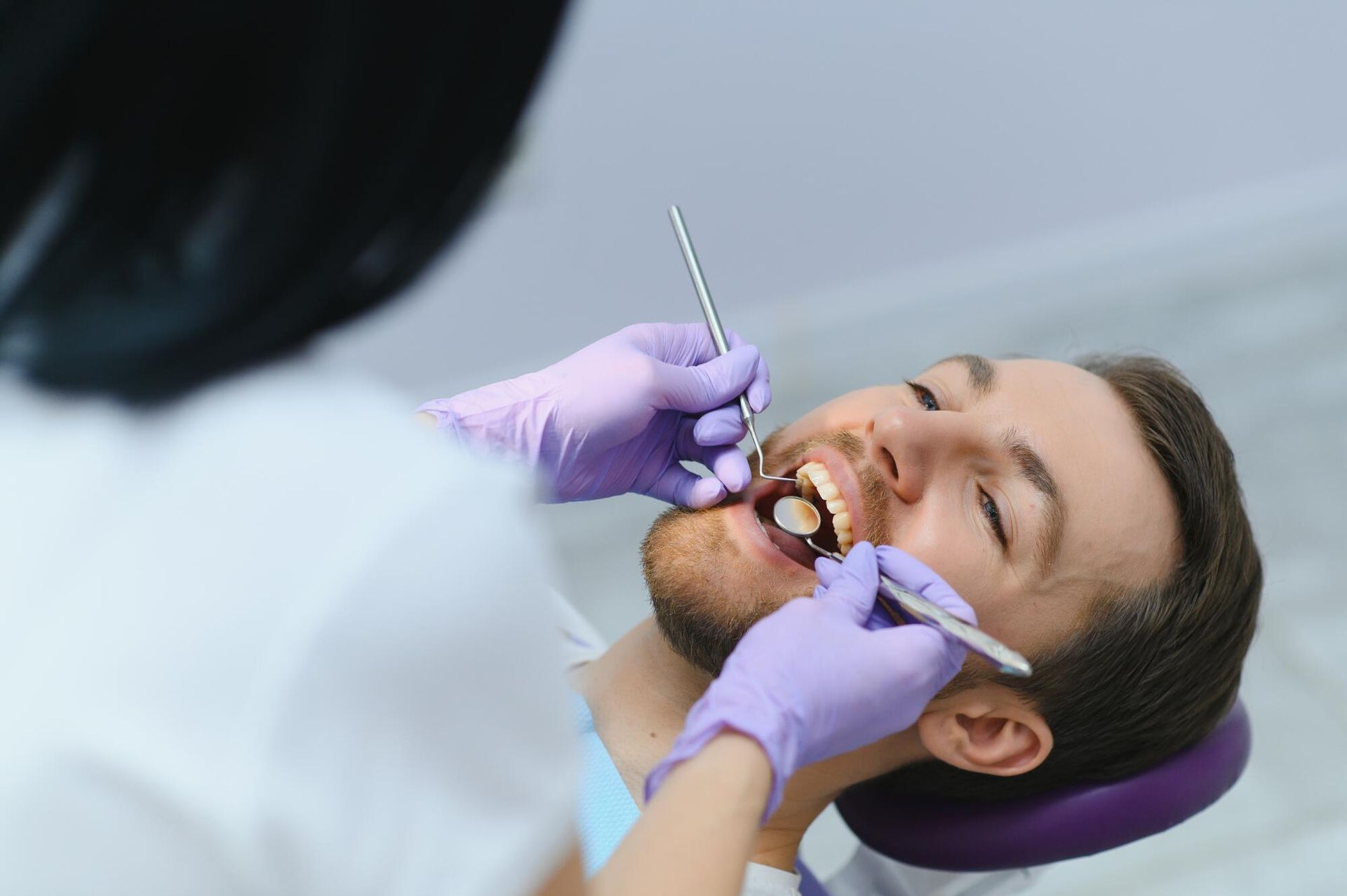 A man is having his teeth examined by a dentist.