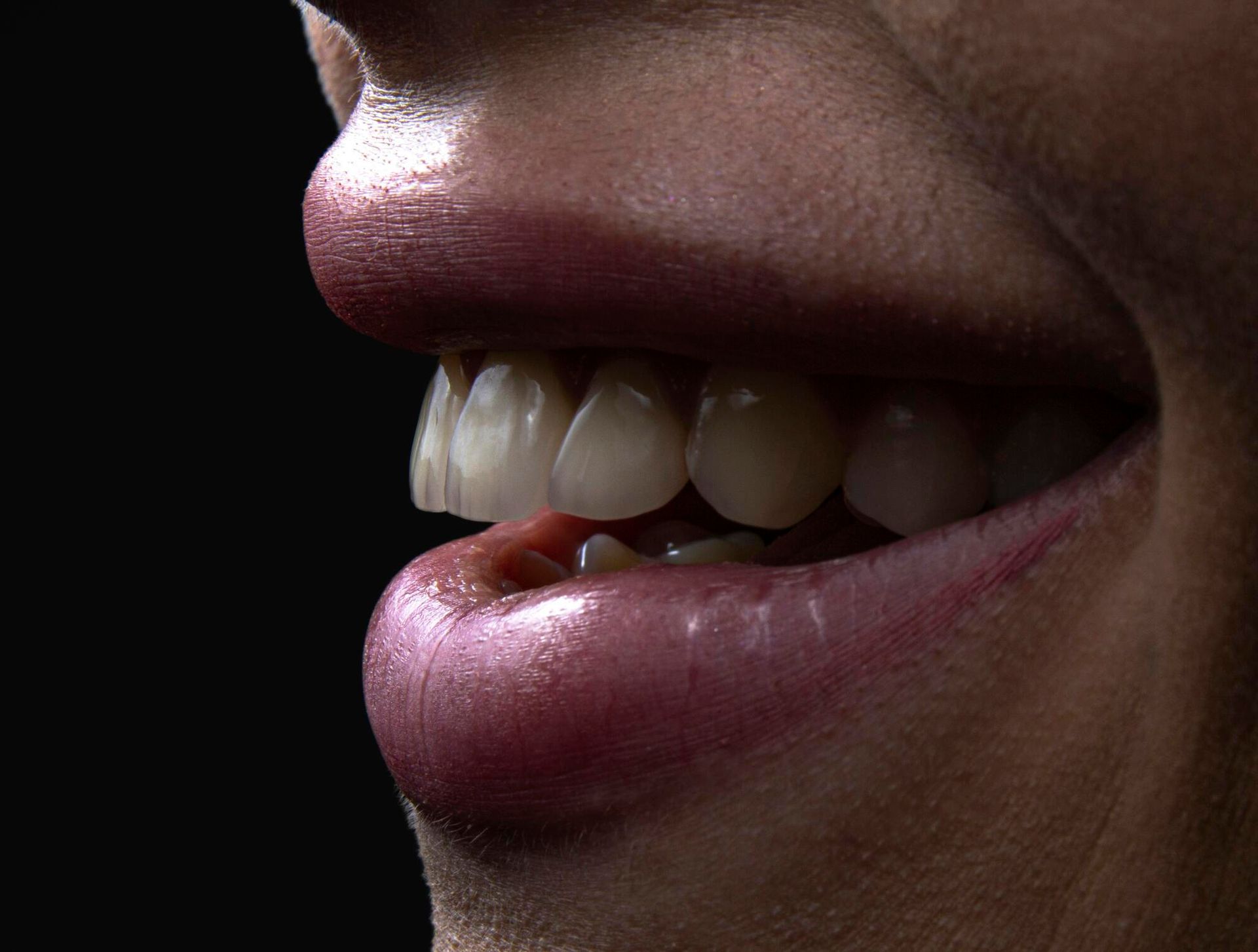 Close-up of a person's smiling mouth, showing white teeth, shiny pink lips, and a dark background.