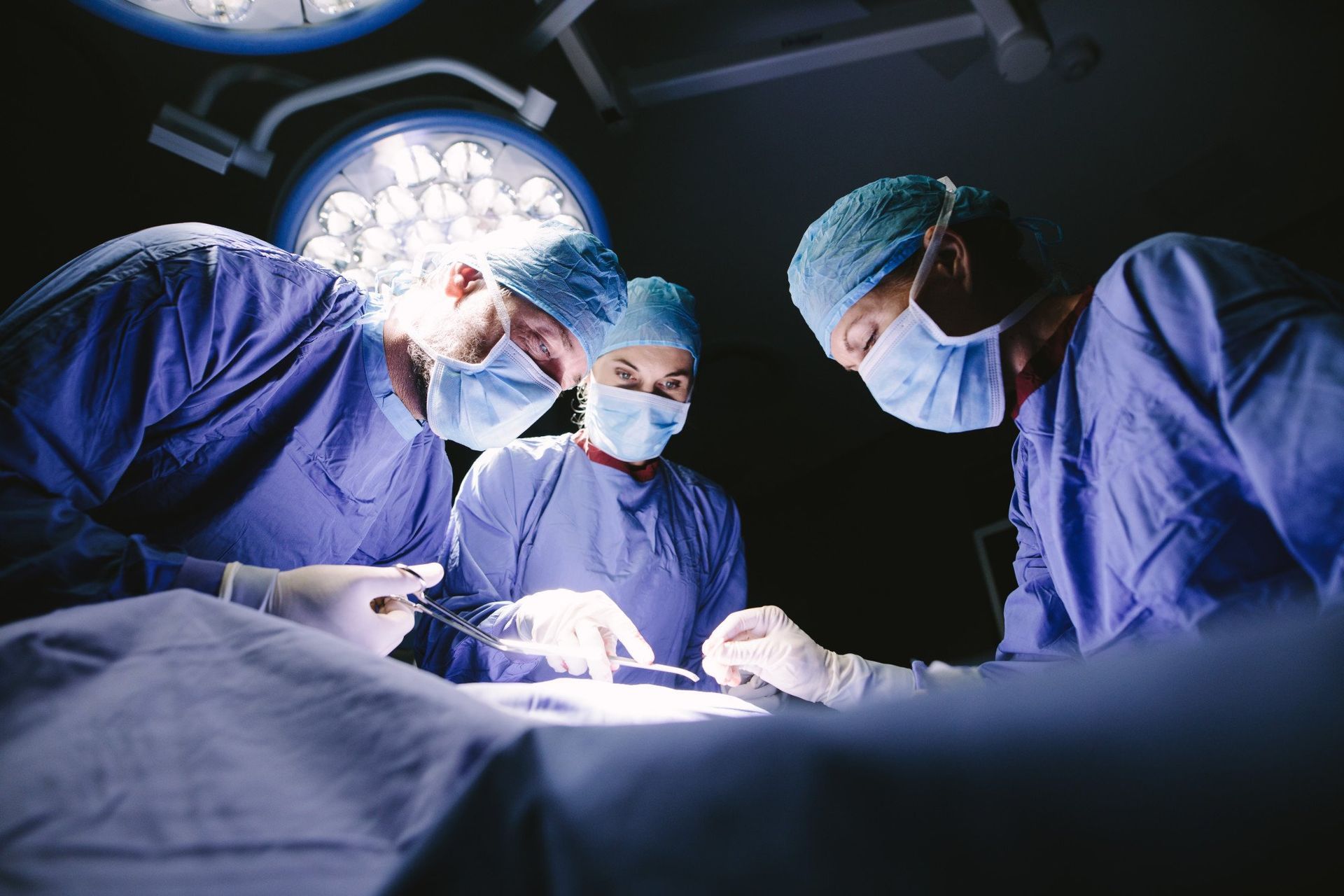three surgeons at work on a patient