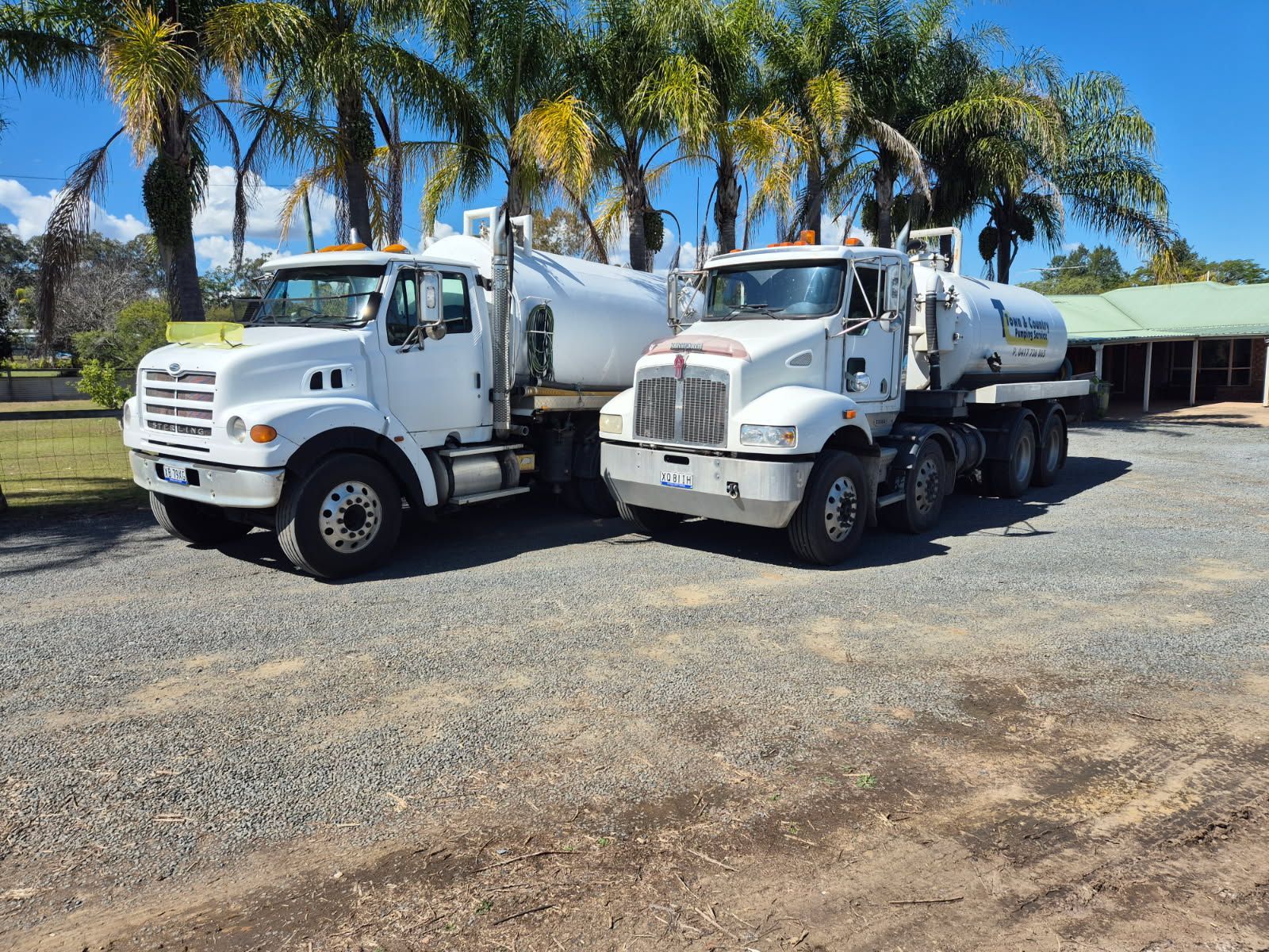 Two workers placing a manhole cover on concrete, outdoors. One wears orange work pants.