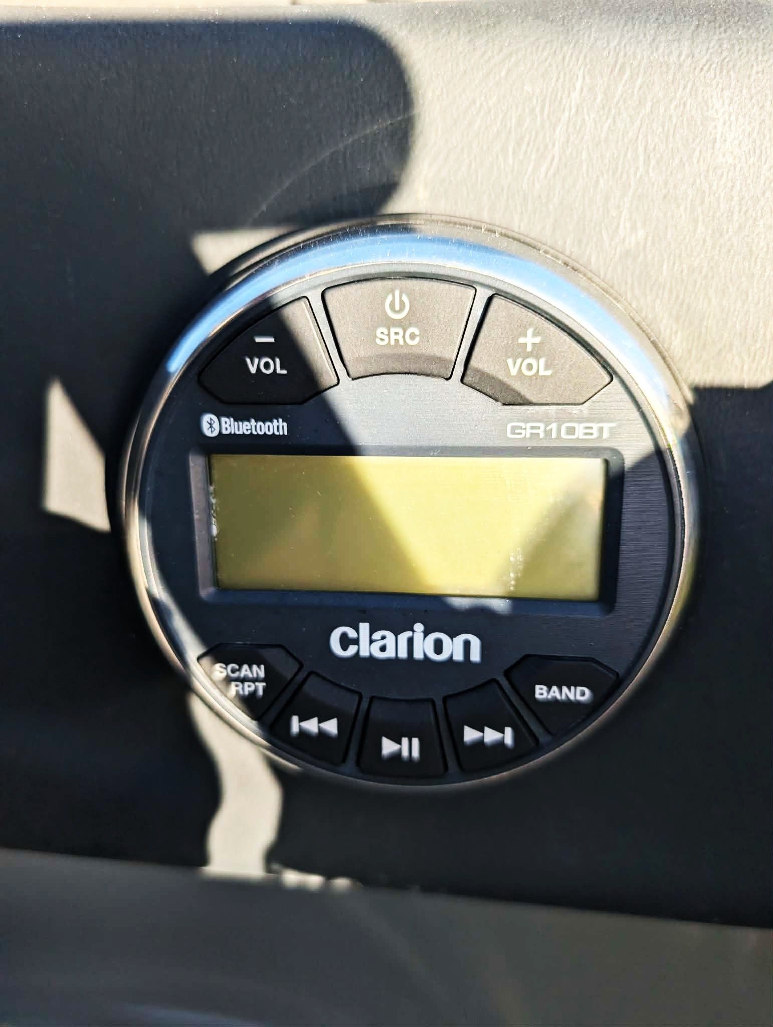 Close-up of a Clarion car stereo with a blank LCD screen and black buttons on the dashboard
