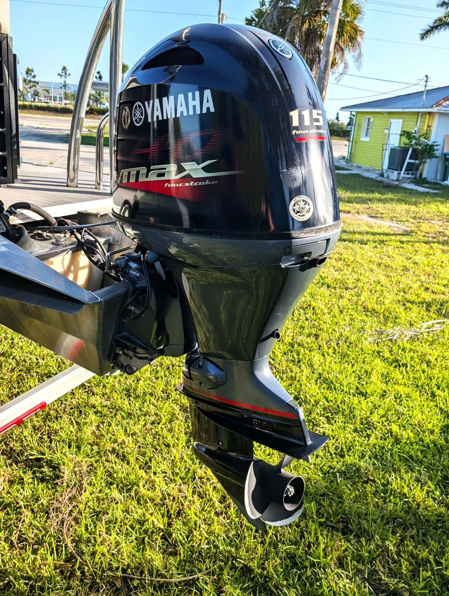 Close-up of a black Yamaha 115 outboard motor mounted on a boat in a sunny yard.