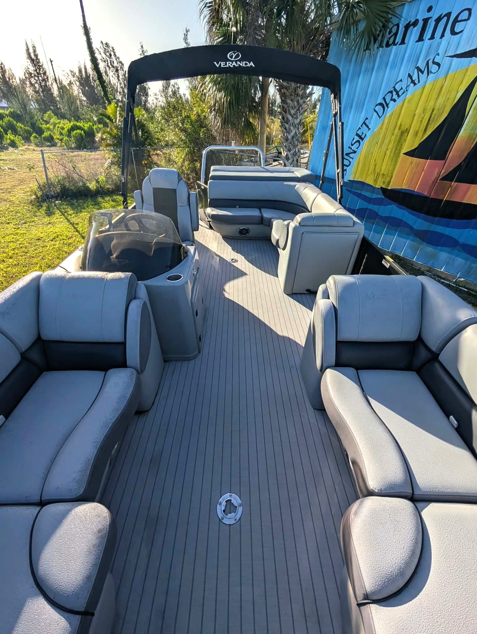 Boat deck with gray cushioned seating and a canopy, viewed from the stern on a sunny day