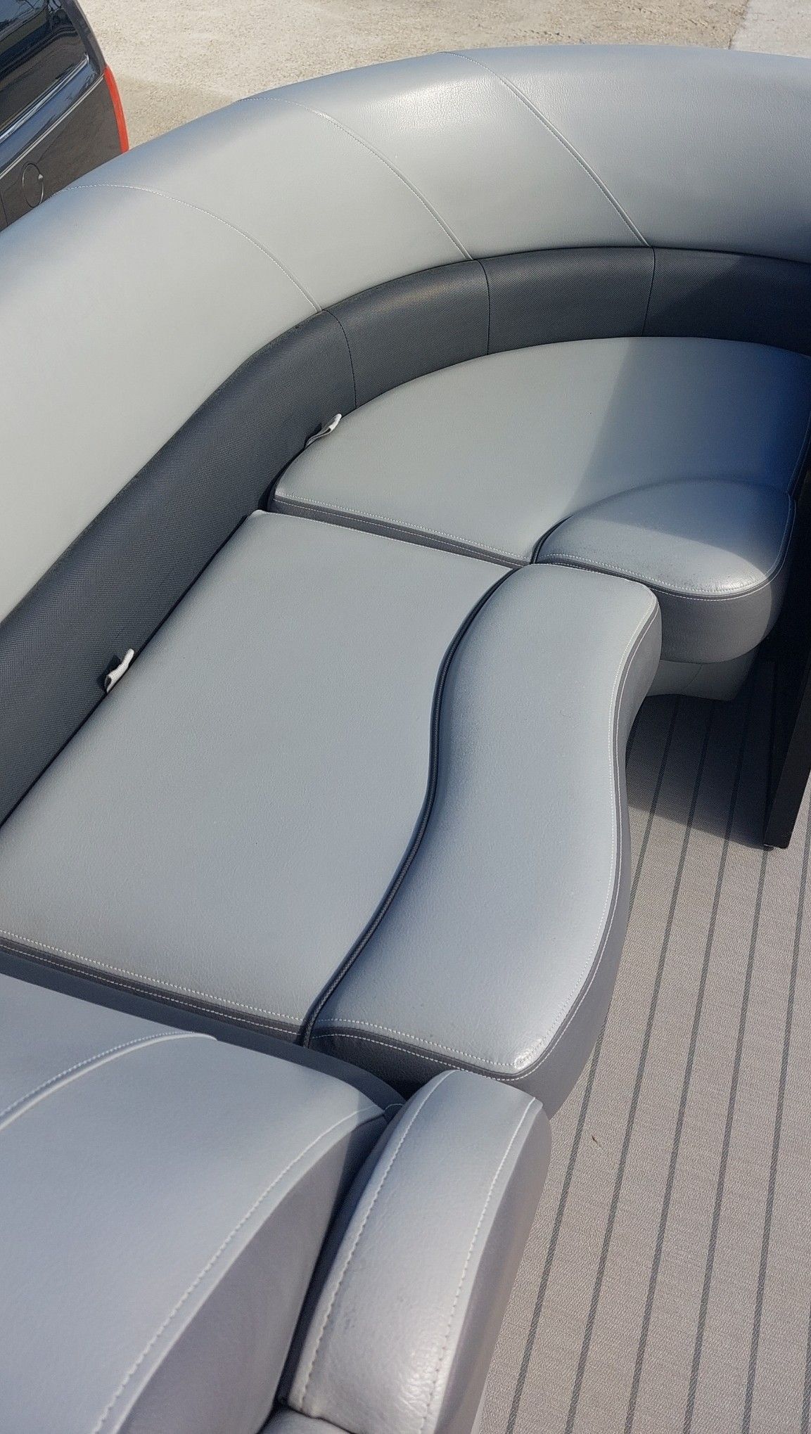 Gray leather boat seating with curved cushioned bench and ribbed floor panel